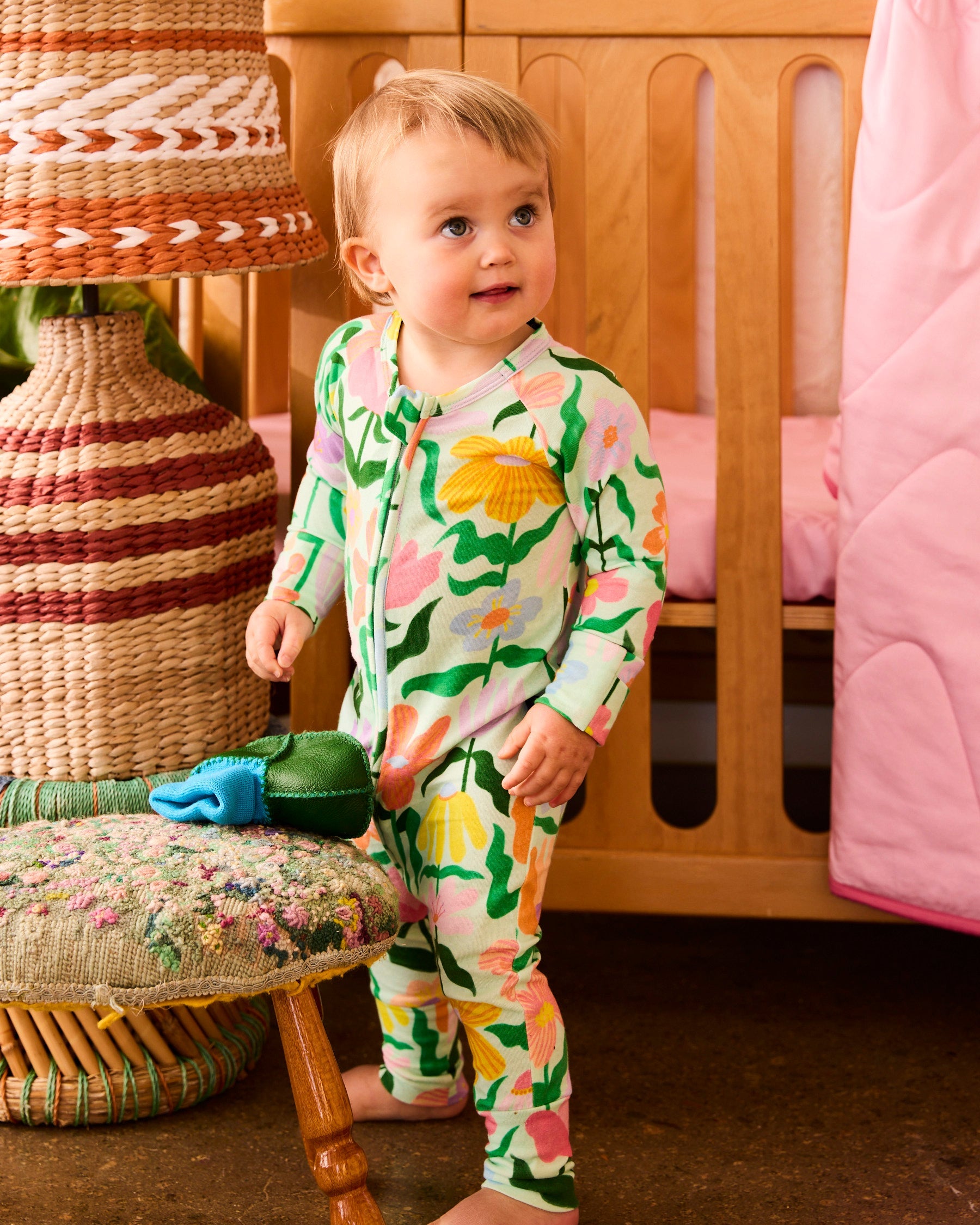 Baby wearing Kip & Co Popping Flowers Green Organic Long Sleeve Zip Romper in nursery setting