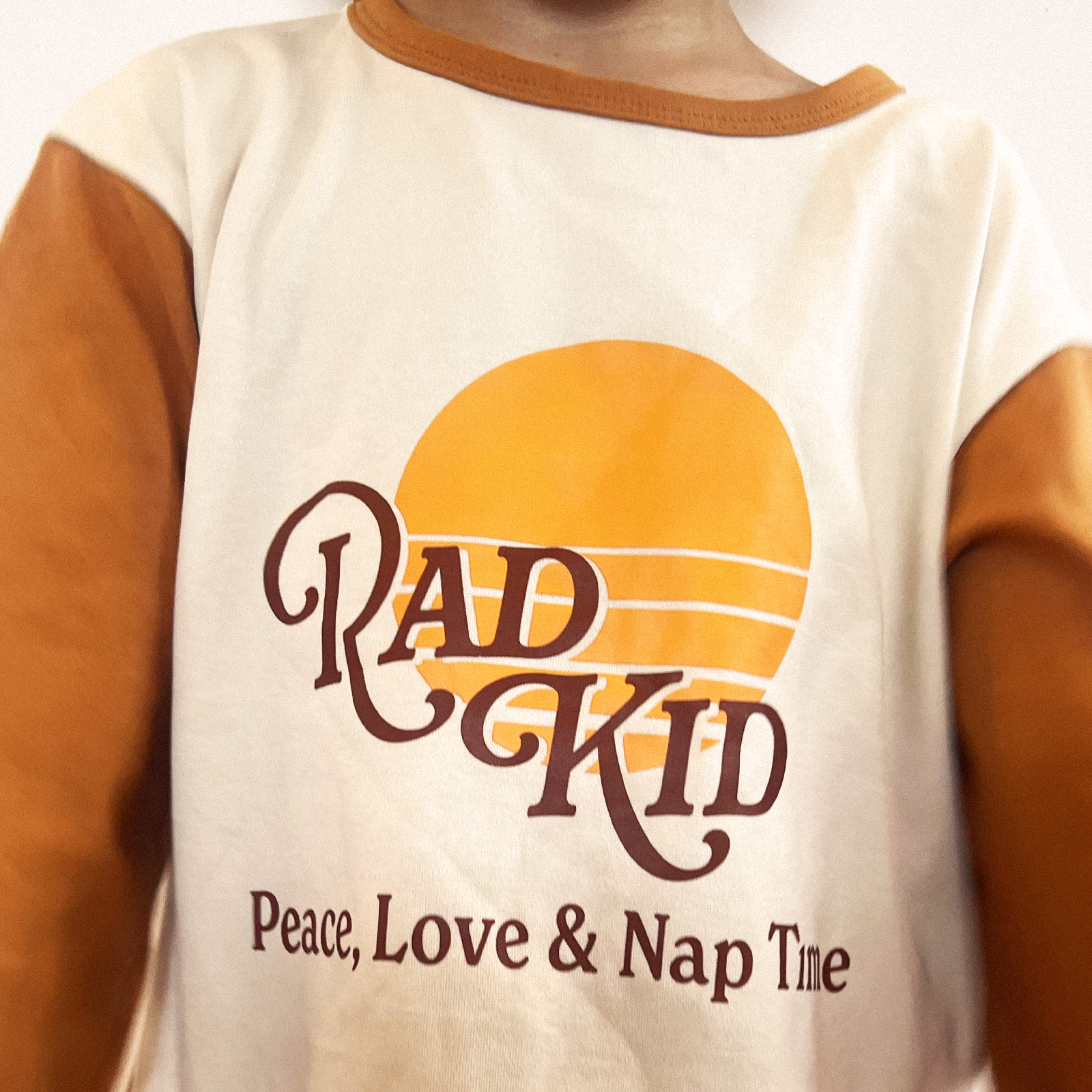 Full body view of Rad Kid Sunsets pajama set featuring retro logo and orange grid pattern pants
