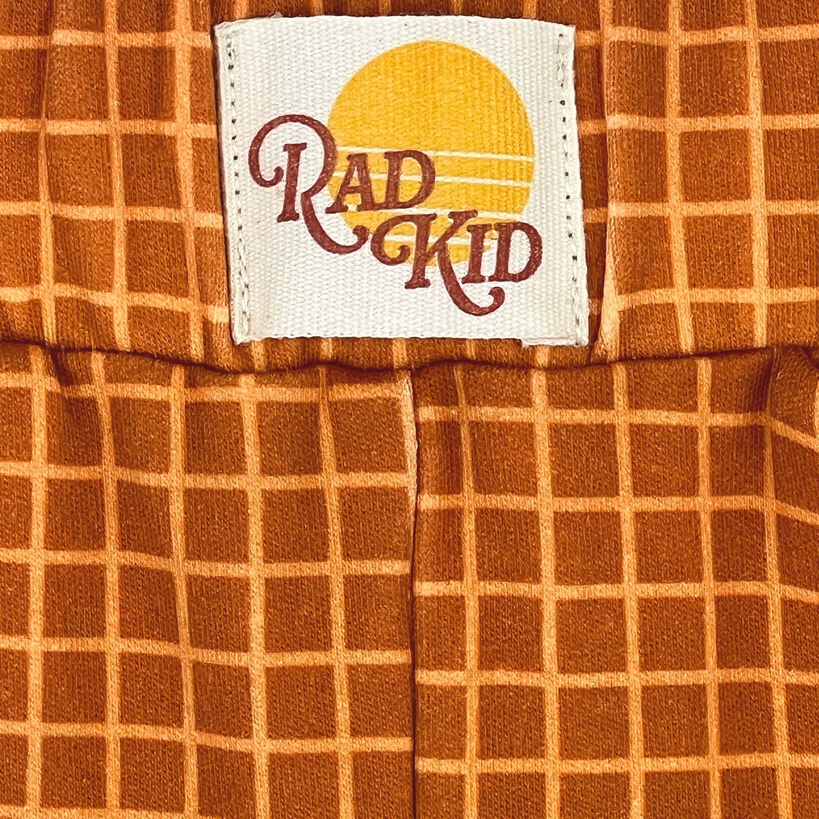 Child standing on bed wearing complete Rad Kid Sunsets pj set with sunset wall art backdrop