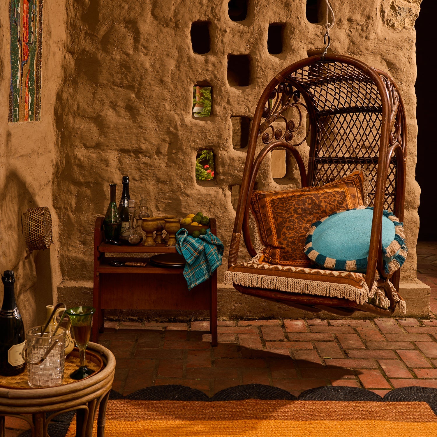 Turquoise round cushion with teal and natural fringe edge styled in a hanging rattan egg chair