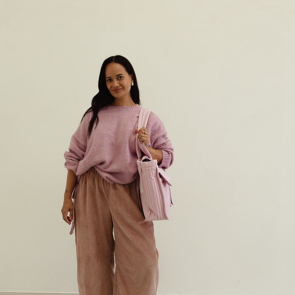 Front view of musk pink corduroy pants styled with oversized knit sweater showing full silhouette