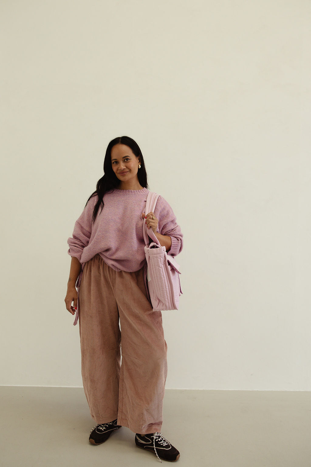Front view of musk pink corduroy pants styled with oversized knit sweater showing full silhouette