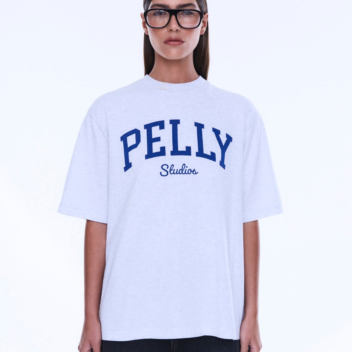 Front detail of Sophia Relaxed Tee featuring blue PELLY Studios collegiate-style lettering on white cotton fabric