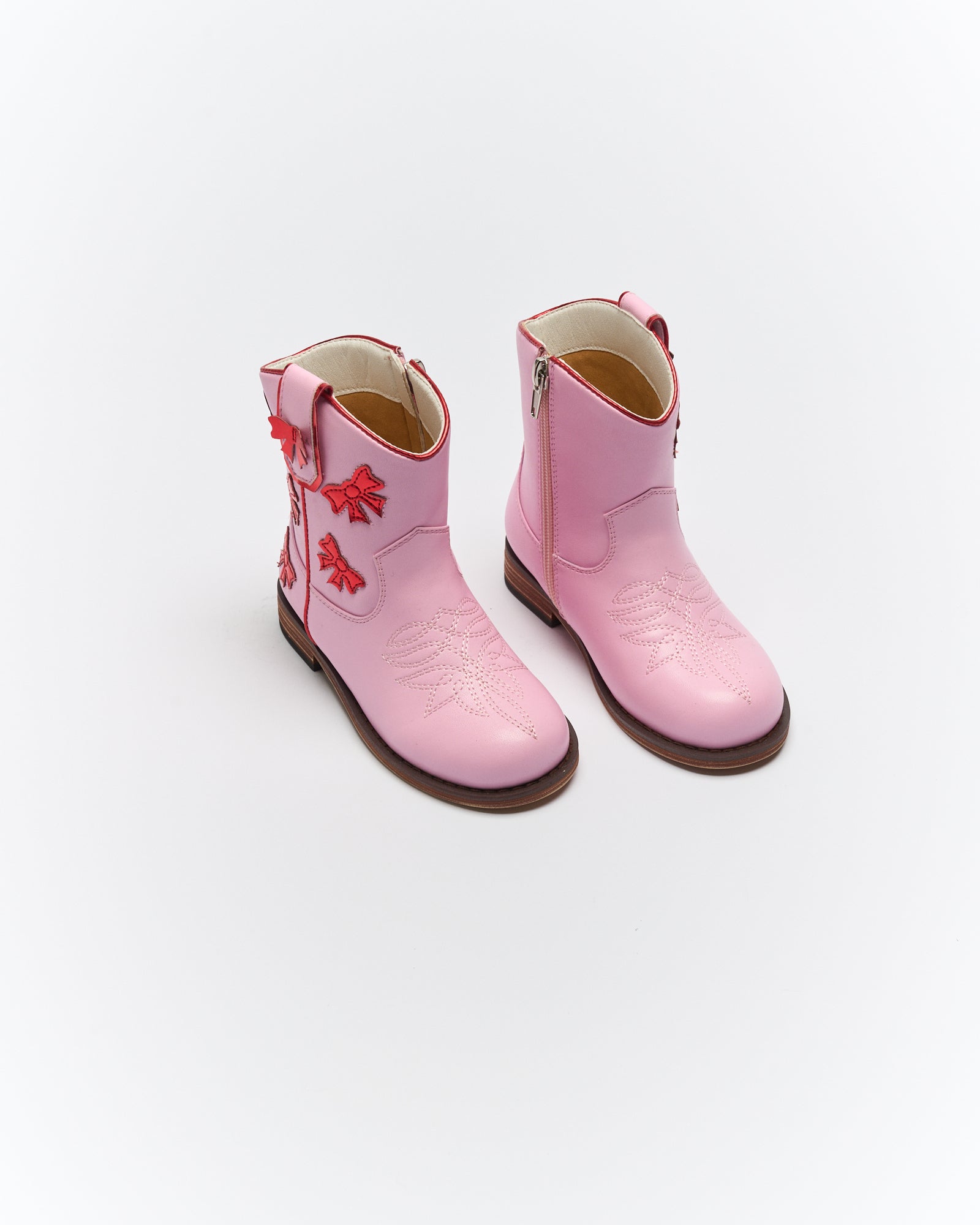 Pink Sadie cowboy boots with red rose embroidery and side zippers shown in angled front view