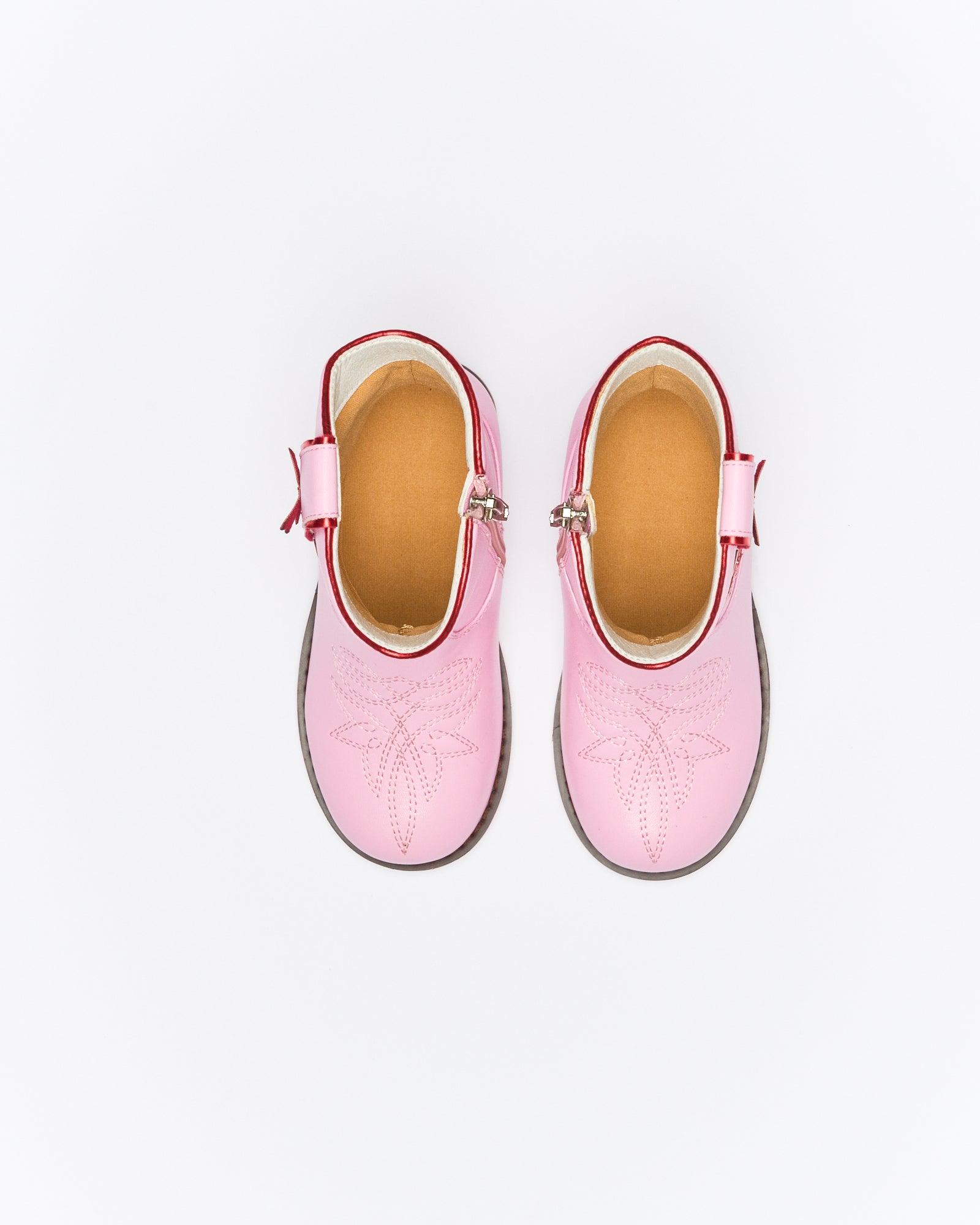 Top-down view of pink Sadie boots showing tan leather insoles and adjustable ankle straps with buckles