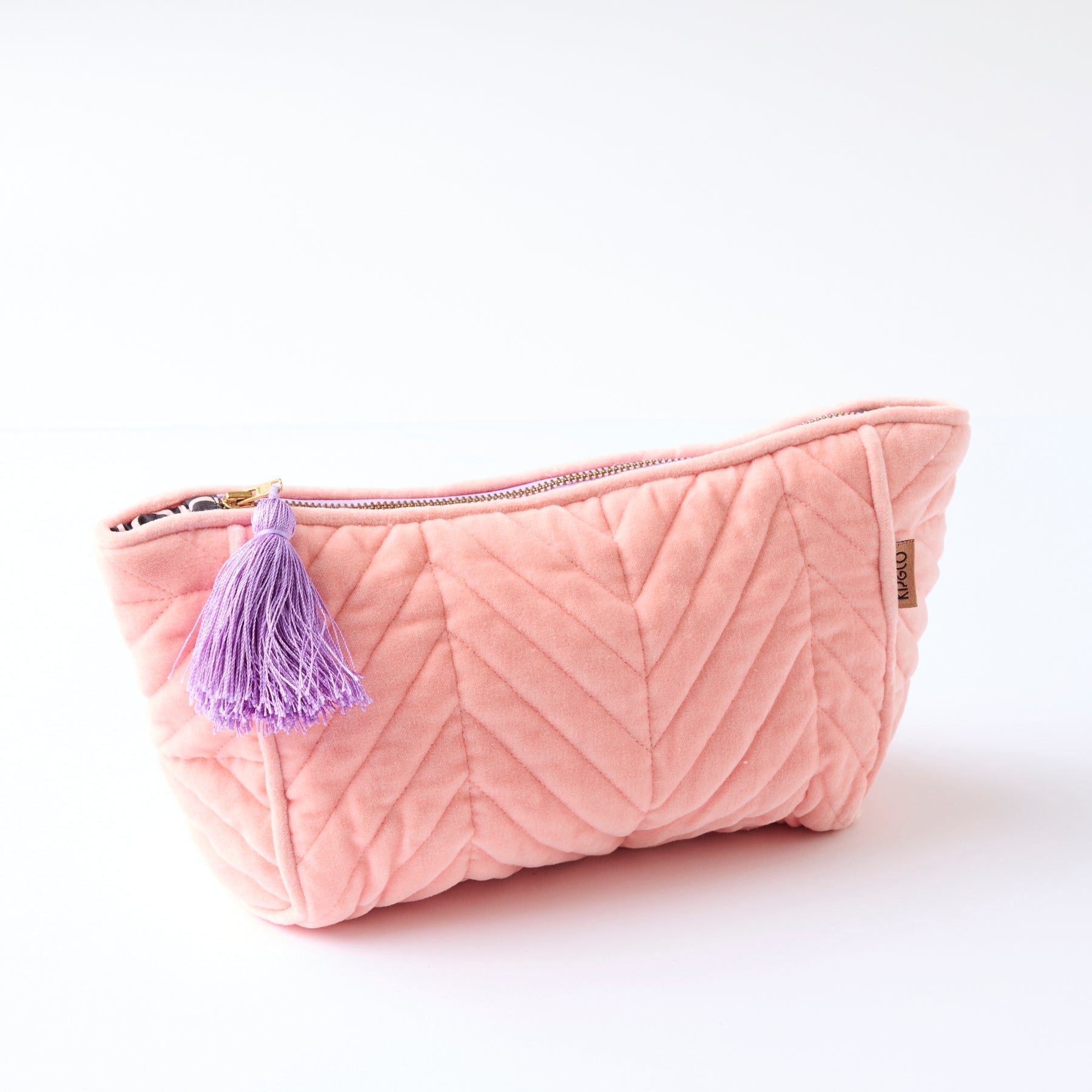 Kip & Co Sherbet Velvet Toiletry Bag in coral pink with quilted chevron pattern and purple tassel charm