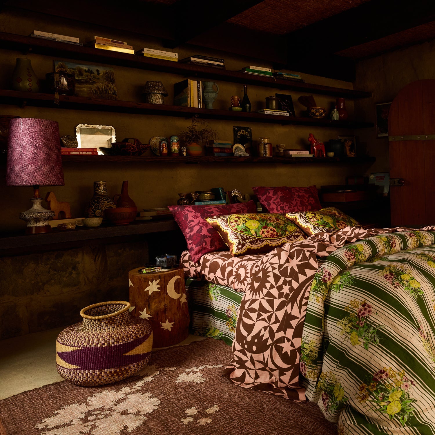 Deep red botanical floral linen pillowcases on a richly styled boho bedroom bed, wide room view