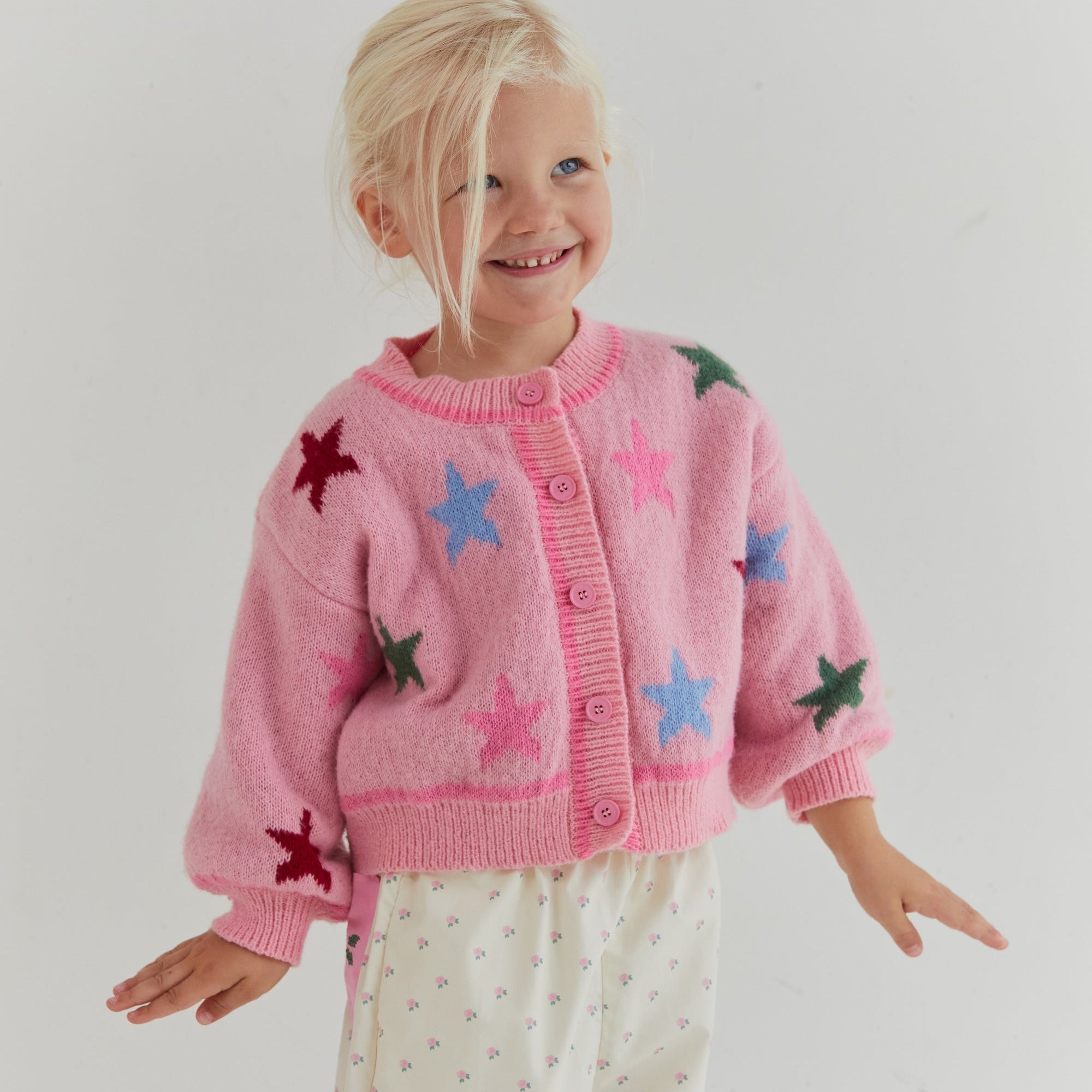 Front view of pink star cardigan showing button closure and colorful star motifs