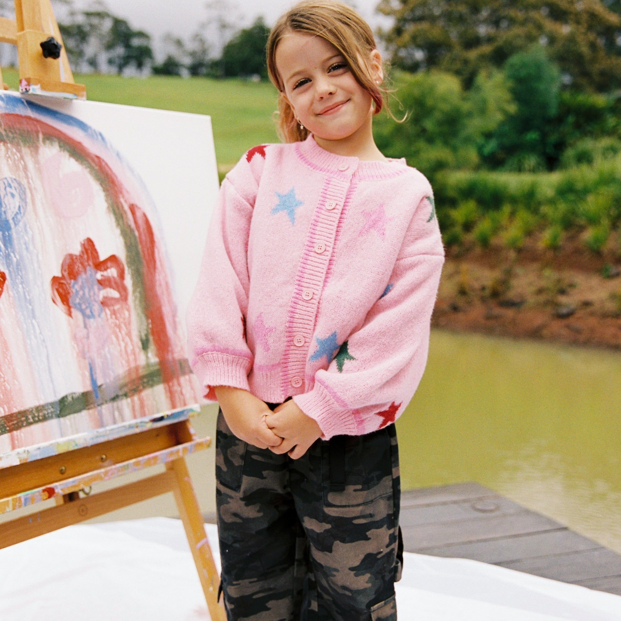 Child wearing pink star cardigan with button front and multicolored star design