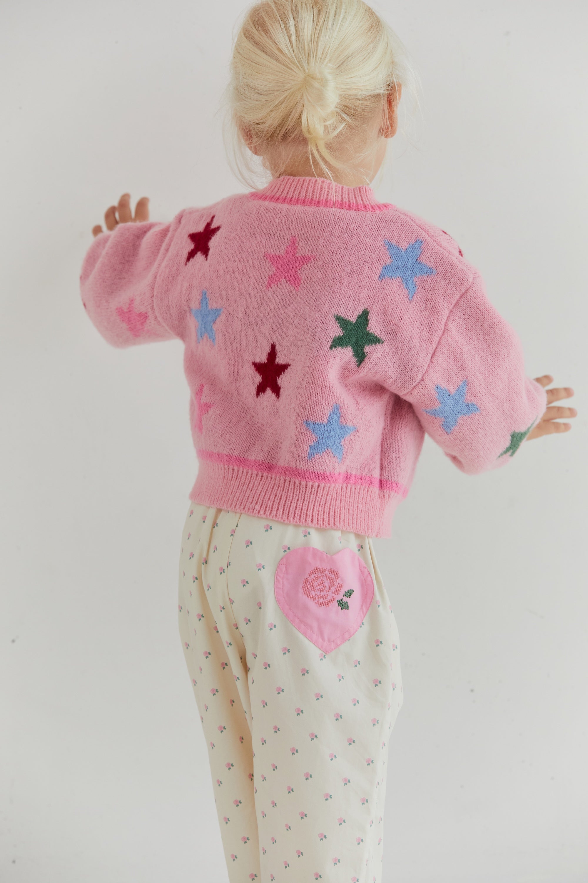 Back view showing star pattern distribution on pink knit cardigan with ribbed collar