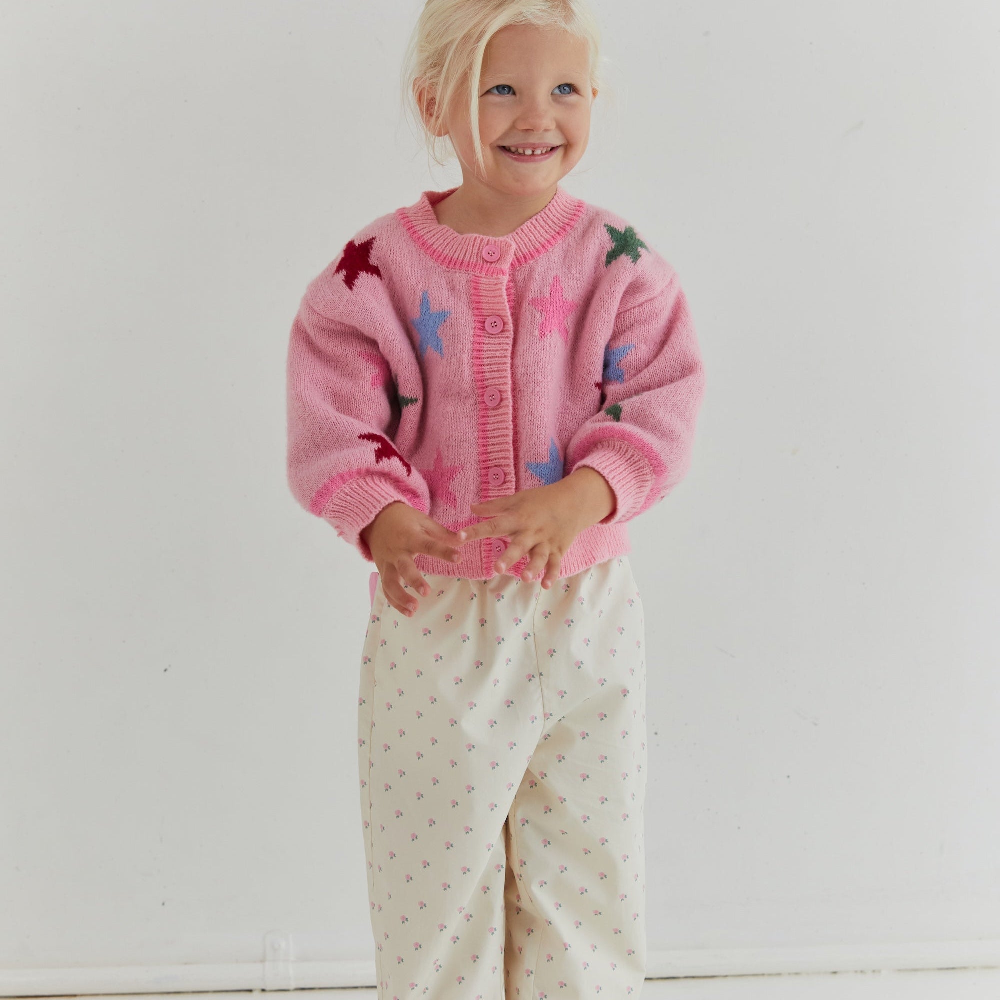 Full front view of pink star cardigan with button placket and crew neckline