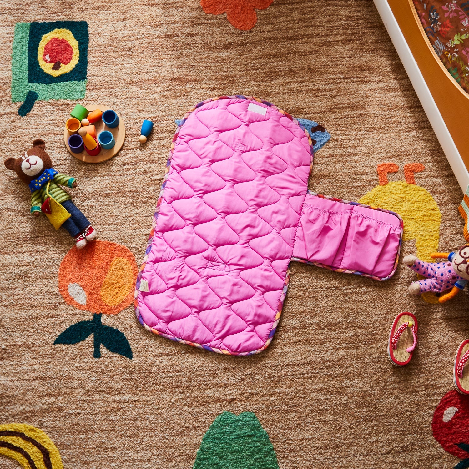 Pink quilted Stela Change Mat showing diamond pattern stitching and side pocket detail on nursery floor