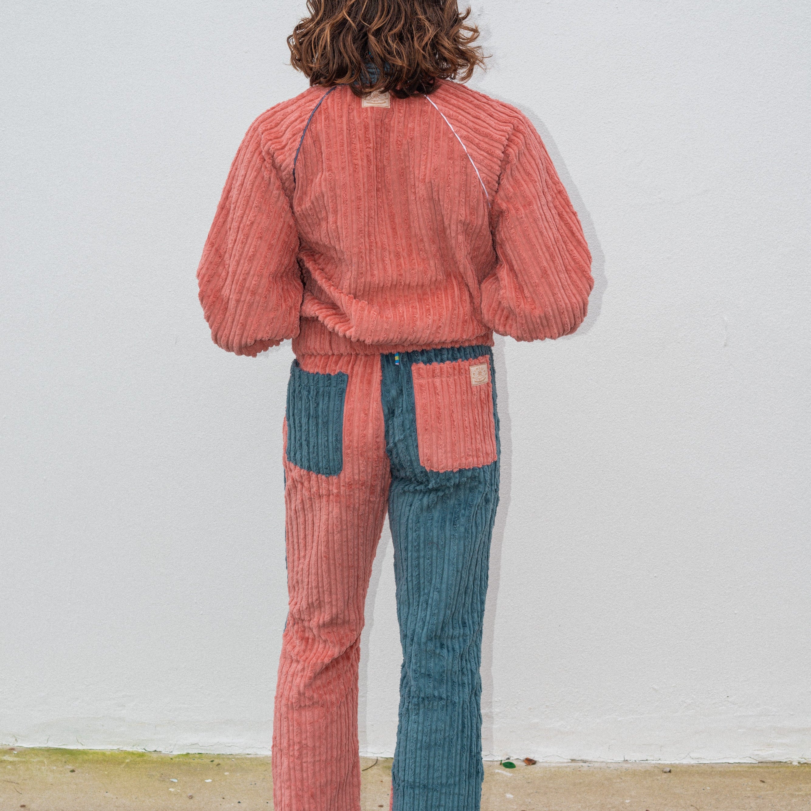 Back view of two tone pink teal corduroy bomber jacket showing ribbed corduroy fabric and raglan seam detail