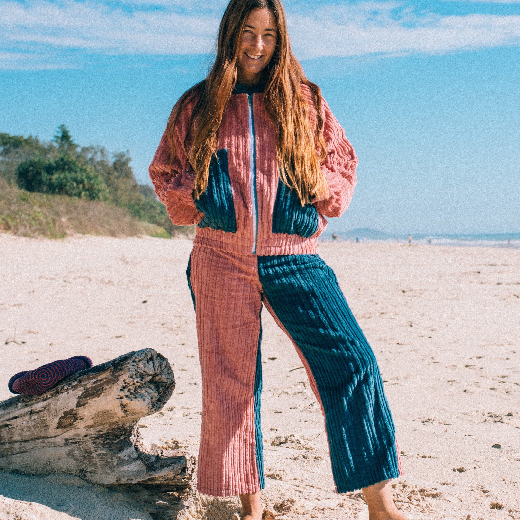 Full length front view of two tone pink blue corduroy surf bomber jacket worn on beach with zip front pockets