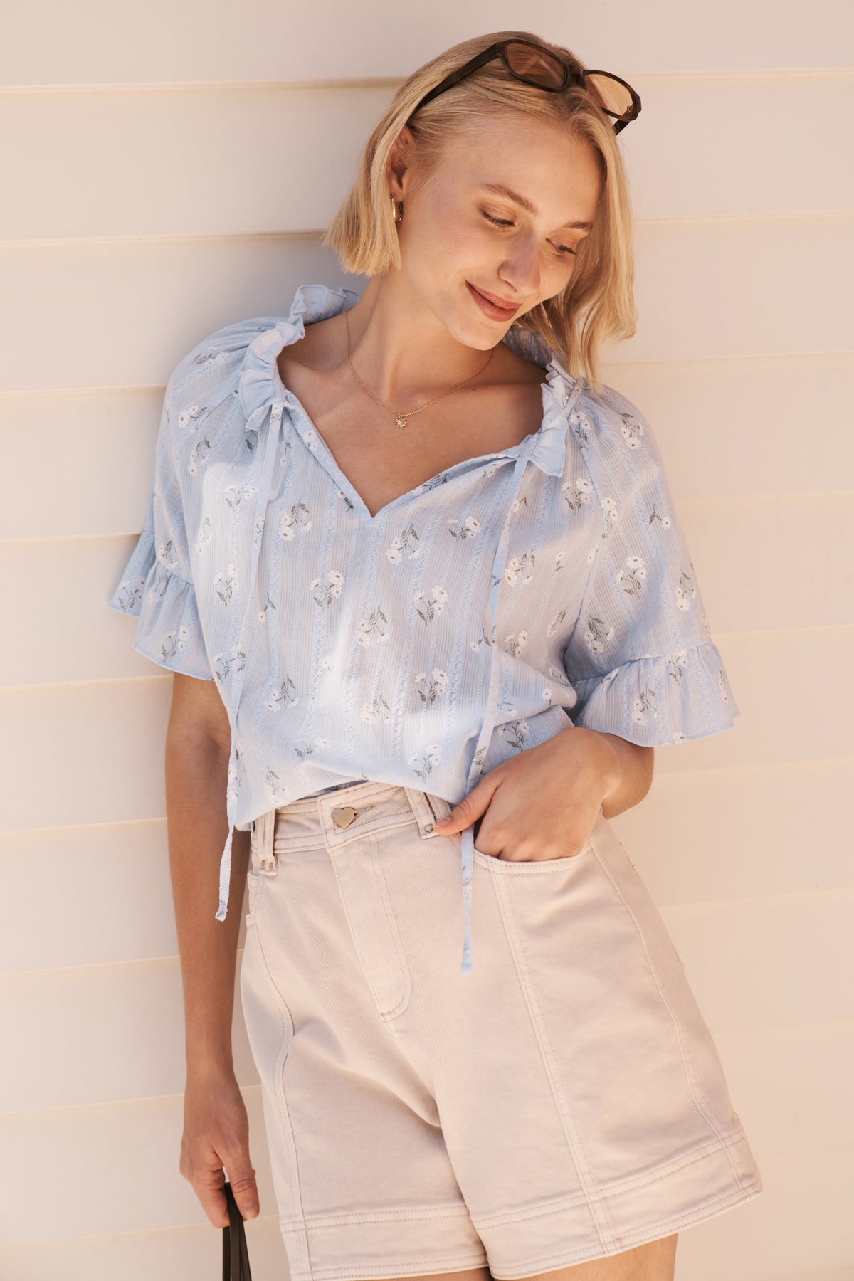 Close-up front view of cream high-waist denim shorts with front pockets and contrast stitching
