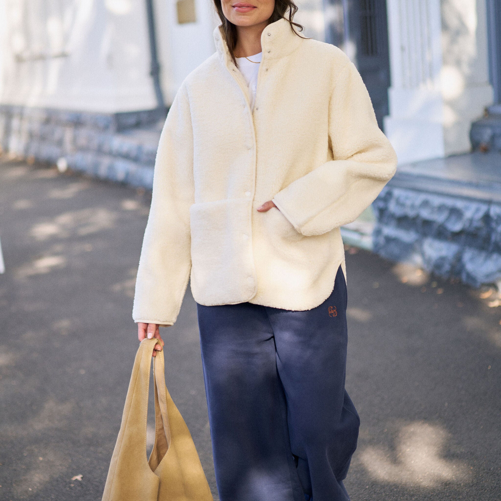 Woman wearing zipped marshmallow teddy jacket with baseball cap in casual street style