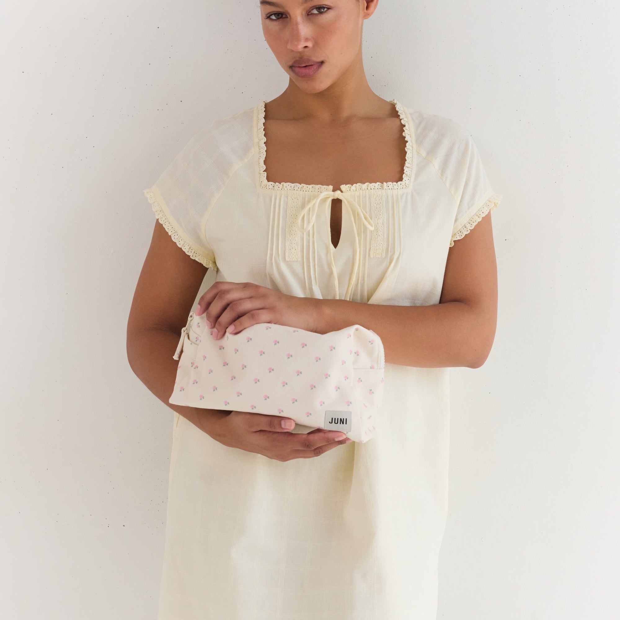 Front view of woman holding cream cotton Essentials Pouch with small pink roses pattern