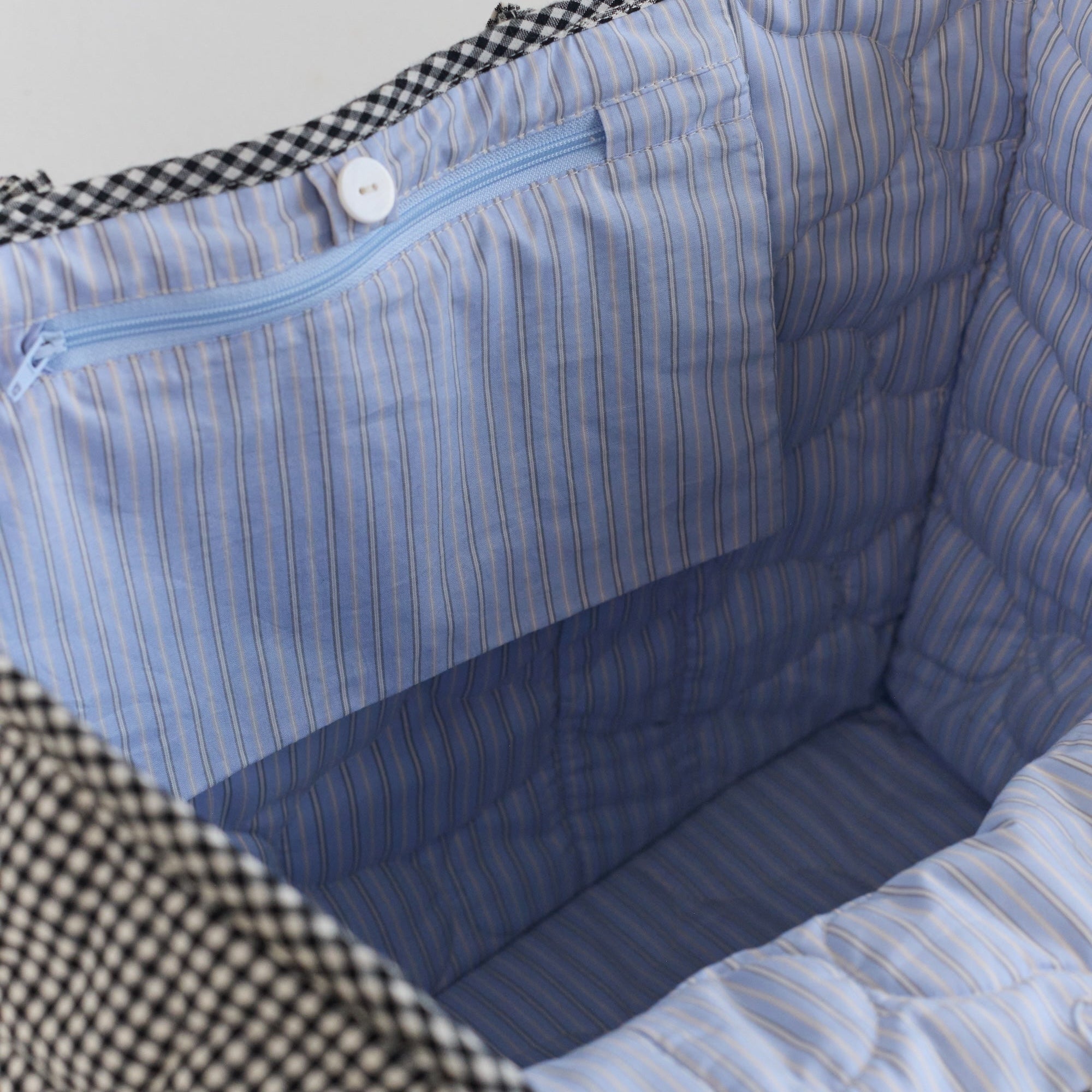 Interior view of Vichy Everything Bag showing blue striped lining and zippered pocket compartments