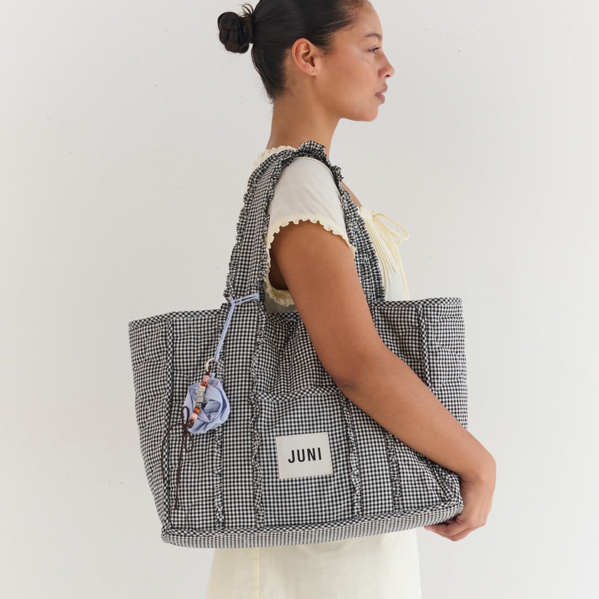 Side view of woman carrying Vichy gingham Everything Bag with quilted texture and rope handles