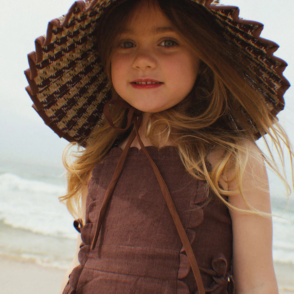 Girl wearing The Freya Linen Dress in Brown by Vika. Paired with a matching Lorna Murray kids hat