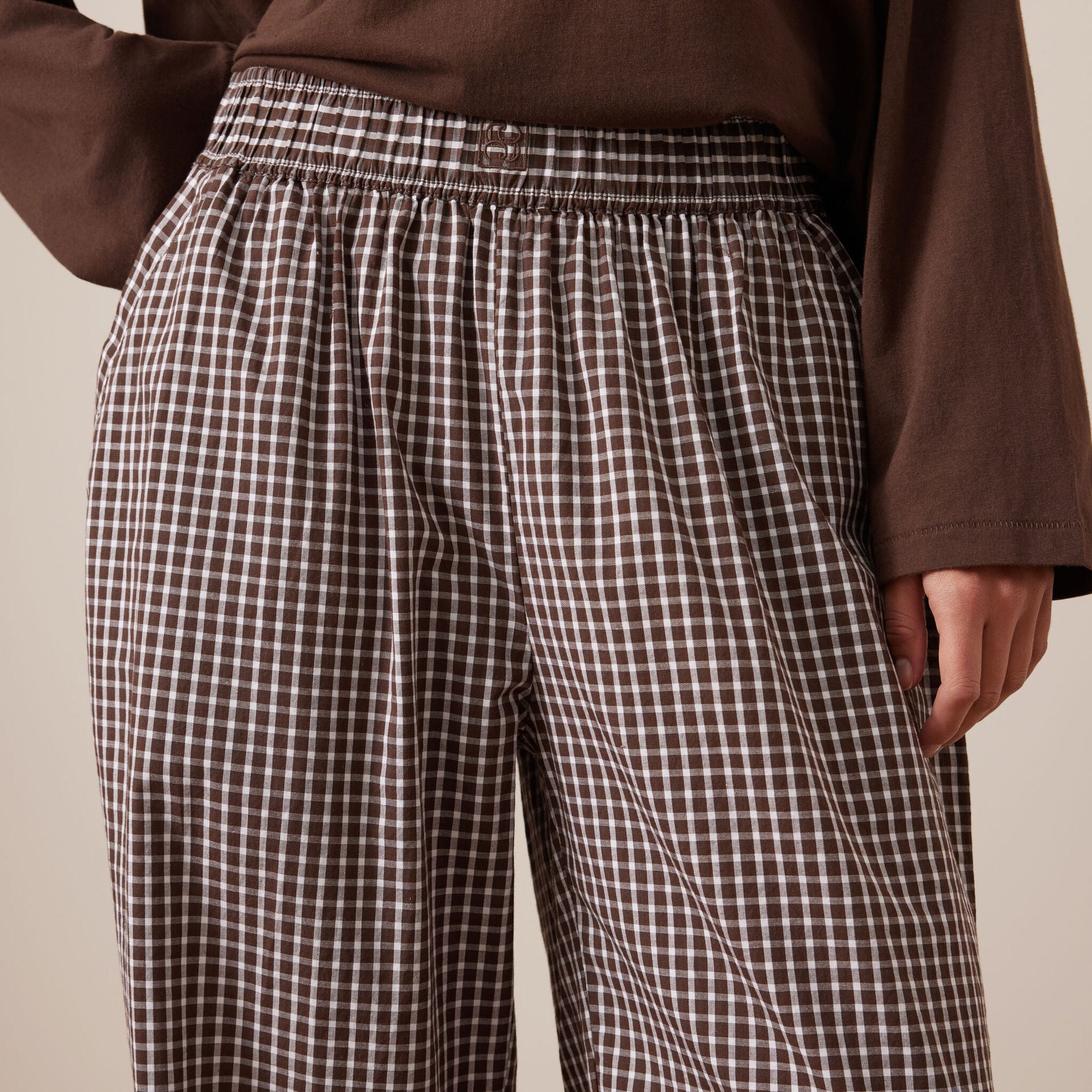 Close-up detail of chocolate check lounge pants showing elastic waistband and gingham fabric texture