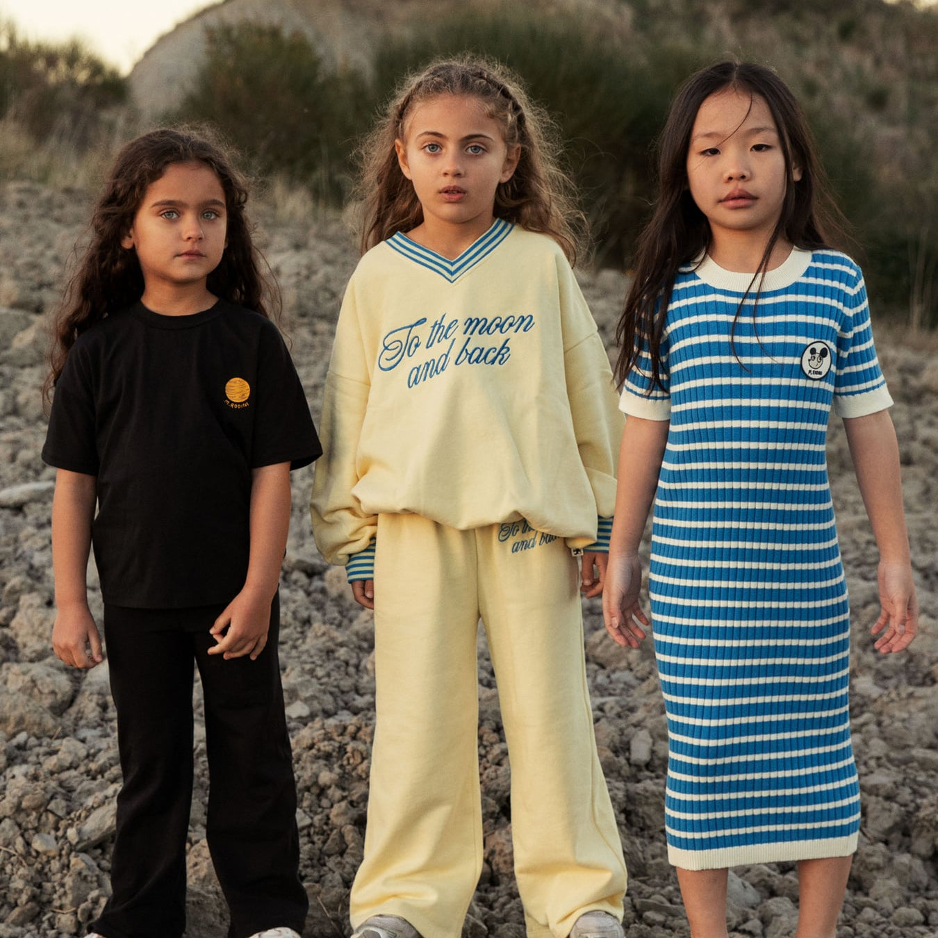 Group styling shot featuring yellow To the Moon sweatshirt with other mini rodini pieces outdoors