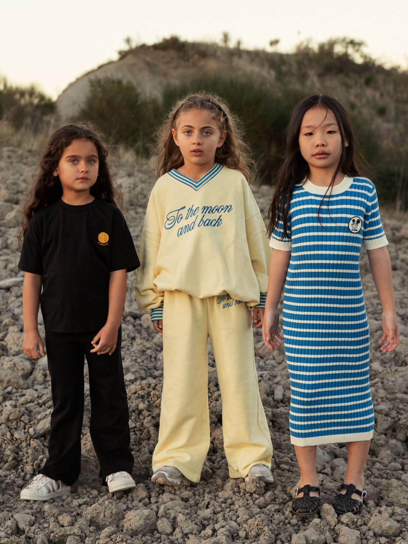 Group styling shot featuring yellow To the Moon sweatshirt with other mini rodini pieces outdoors