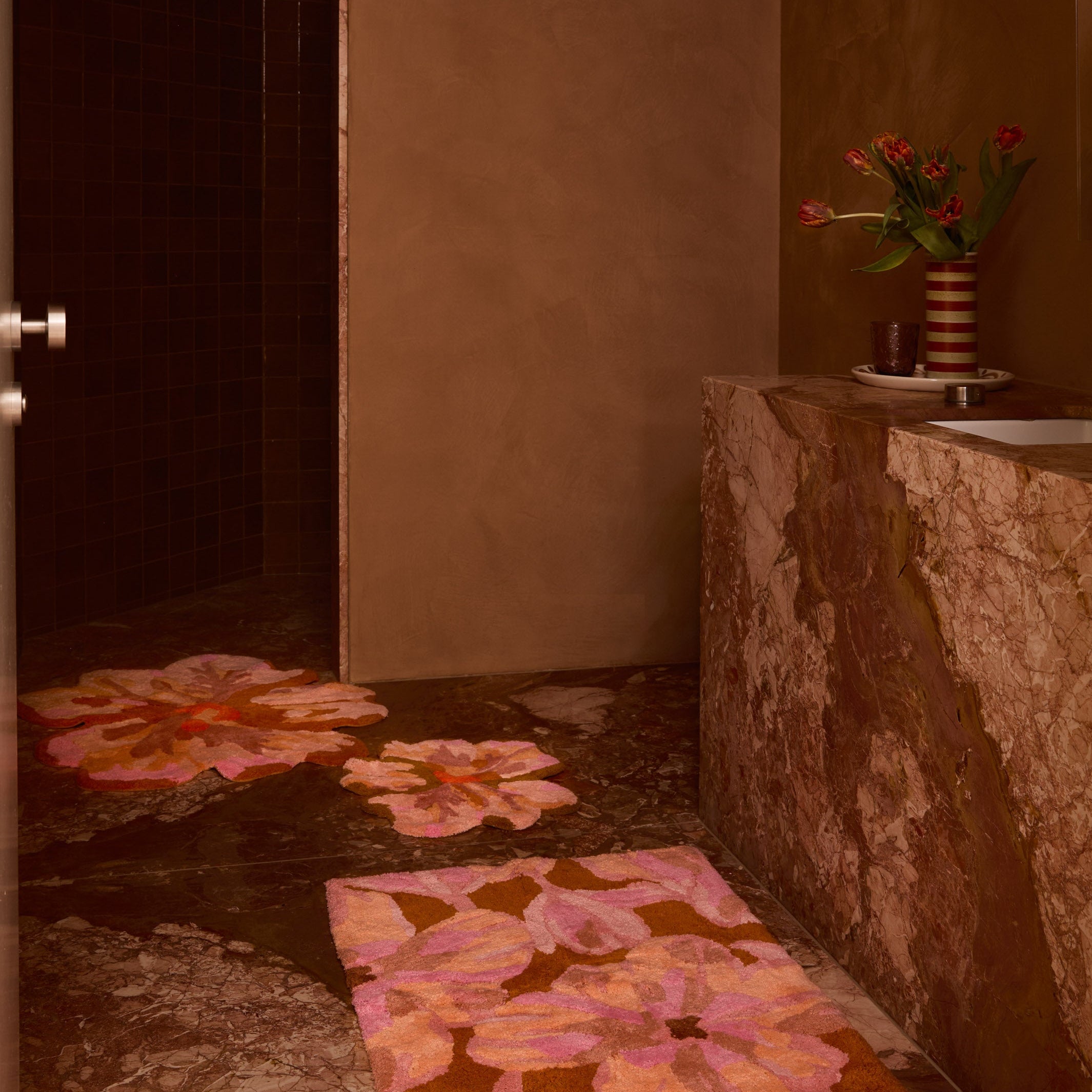 Multiple Tulip Tan Bath Mats arranged in modern bathroom displaying 80cm flower shaped design