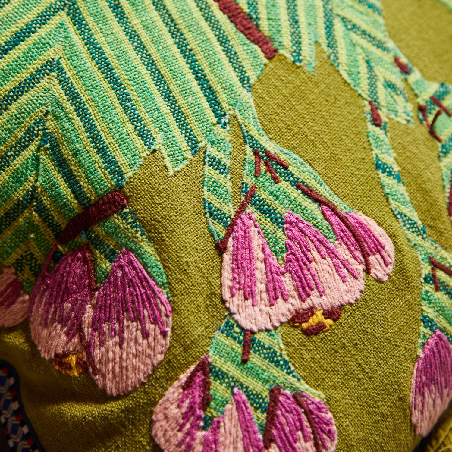 Detail view of embroidered pink flowers and green palm fronds on Vivi Applique Cushion in juniper