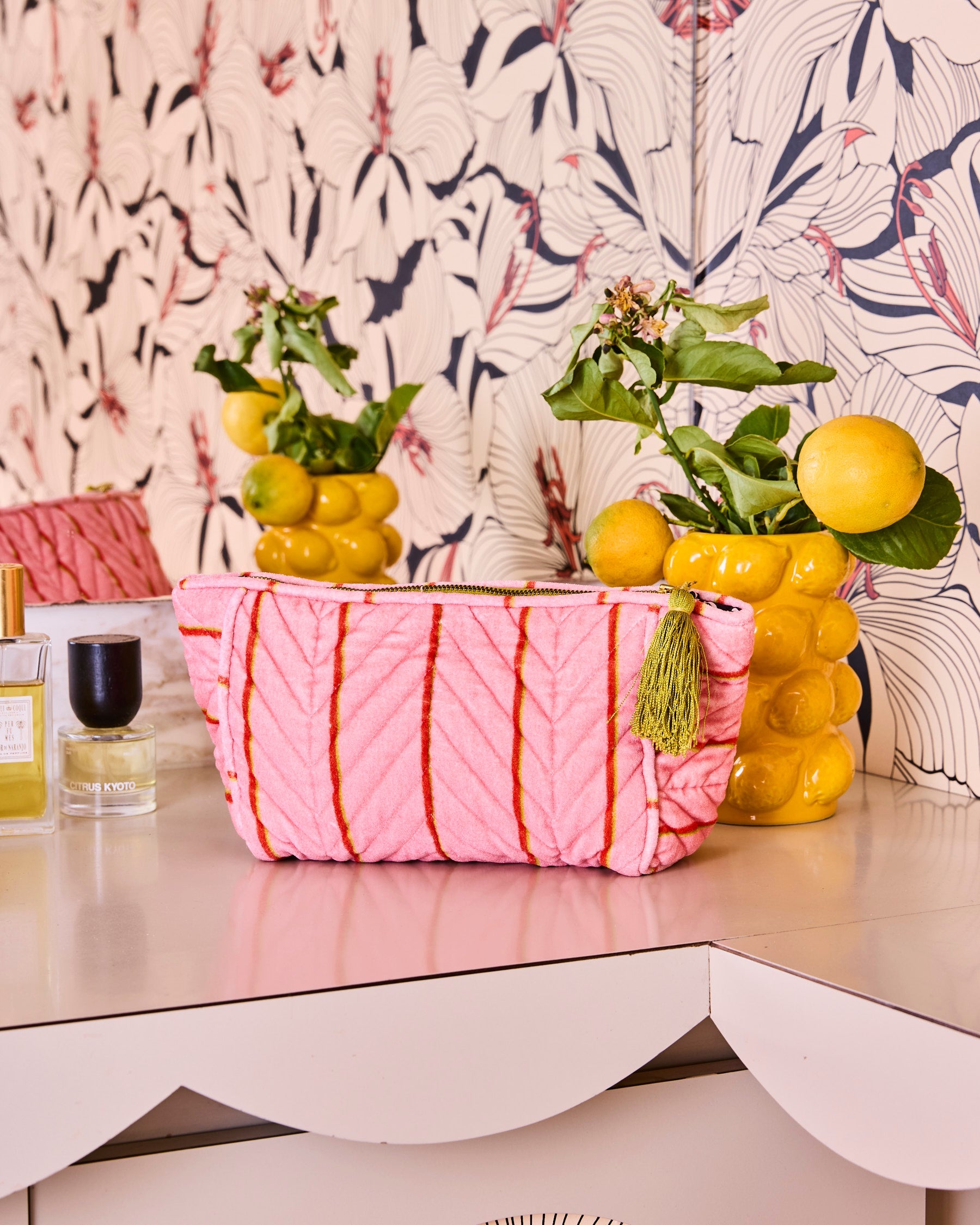 Kip & Co Wategos Soiree Stripe pink velvet toiletry bag styled on vanity with tropical wallpaper and gold tassel