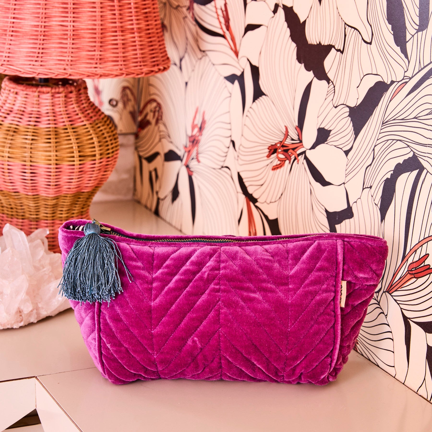 Wild Grape Velvet Toiletry Bag by Kip Co with quilted pattern and teal tassel on neutral surface