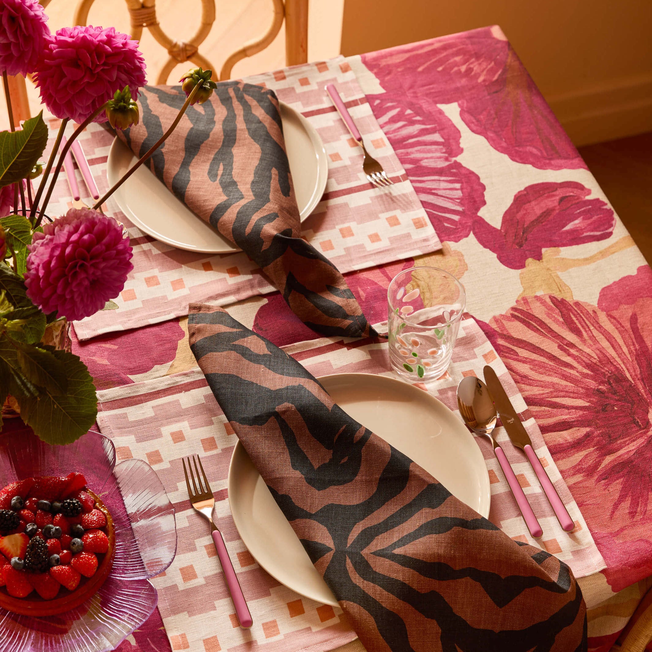 Overhead view of Wild Pansy Pink Tablecloth with place setting and coordinating napkins