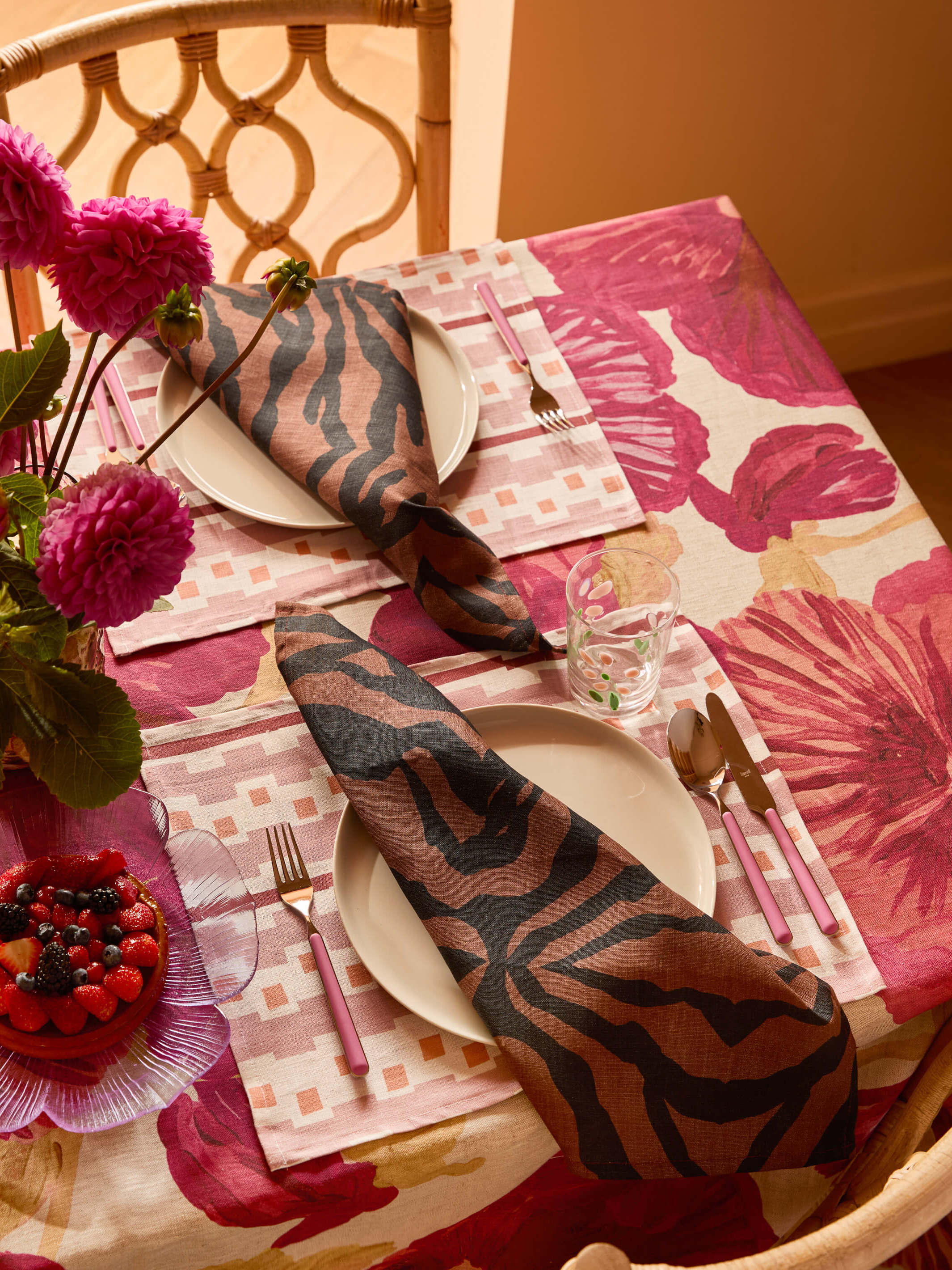 Overhead view of Wild Pansy Pink Tablecloth with place setting and coordinating napkins
