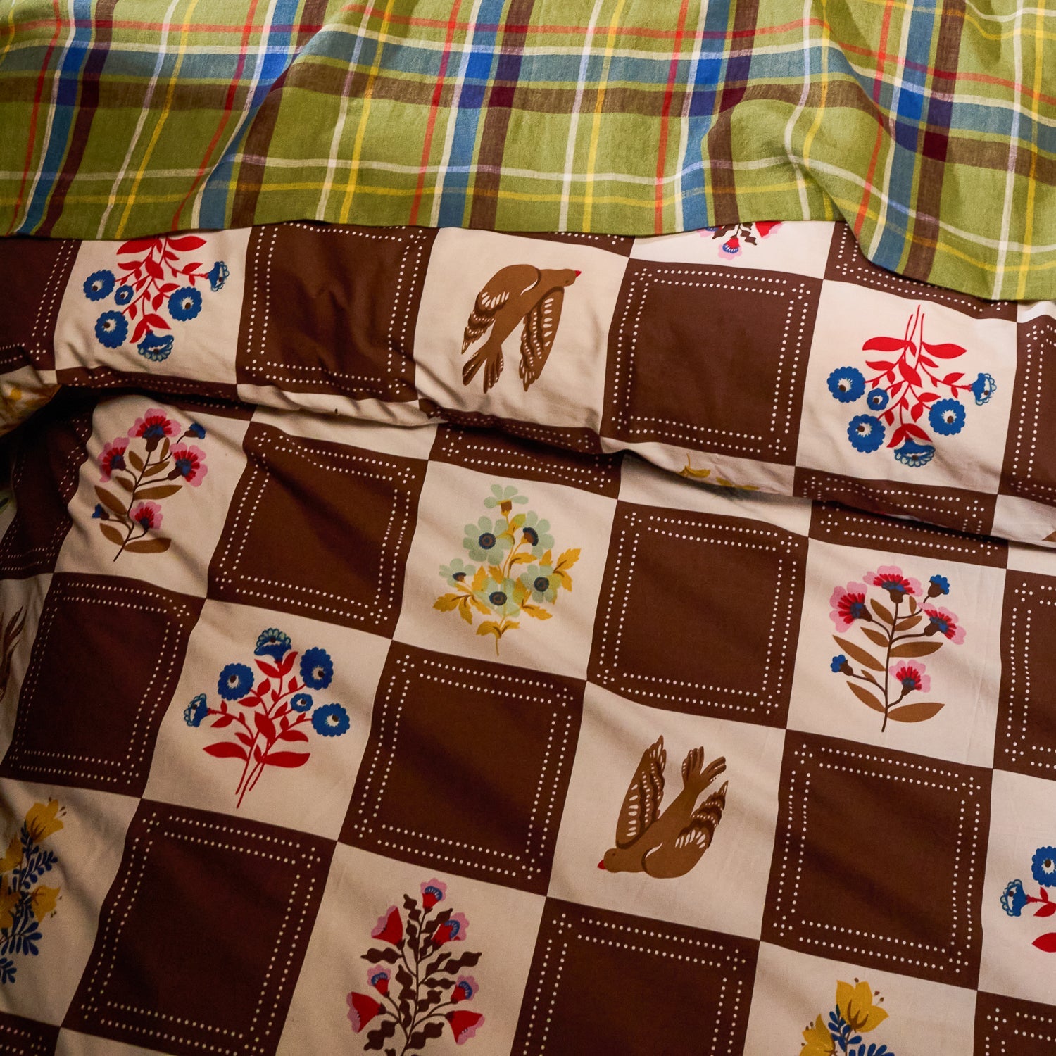 Detail shot of brown and cream checkerboard cotton quilt cover showing bird and multicolour floral print squares