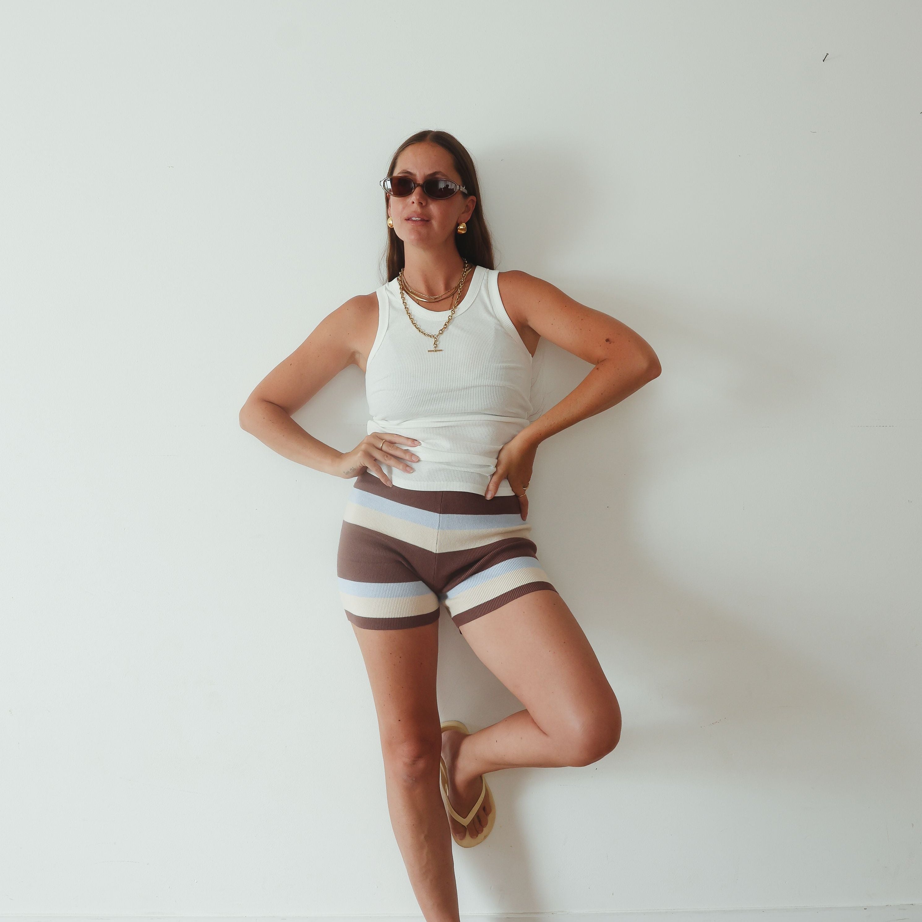 Studio angled view highlighting stripe detail on knit shorts in brown, cream and blue colorway