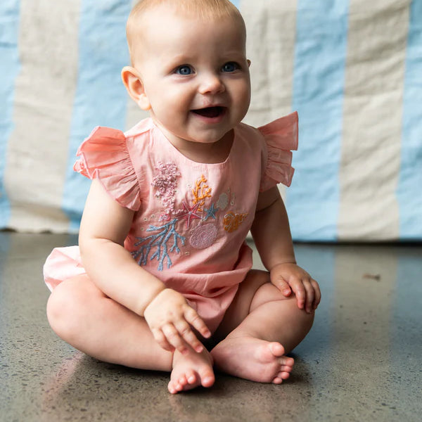 baby wearing pink baby onesie with coral embroidery - great baby shower gift idea