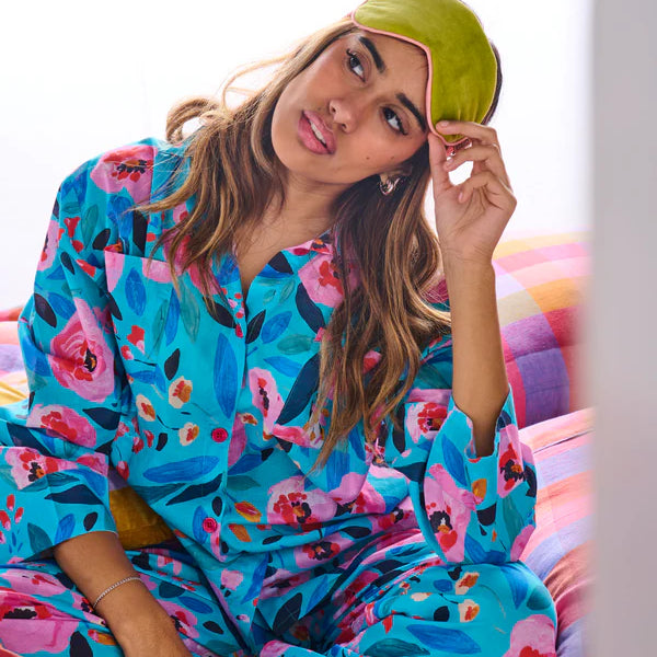 Model wearing the Morning harvest organic cotton long sleeve shirt & pant pyjama set by Kip & Co - red, pink and blue floral pattern