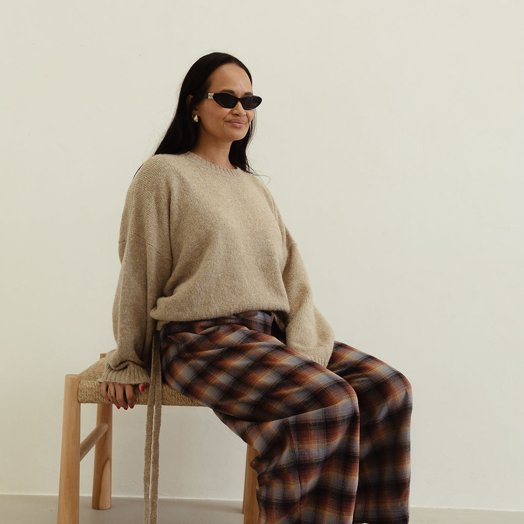 Seated view of Vali check pants displaying brown blue check pattern and wide leg cut