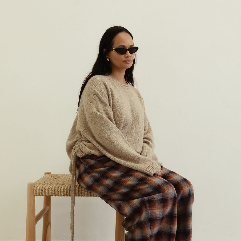 Side seated angle of Vali check pants showcasing brown blue plaid print and relaxed fit