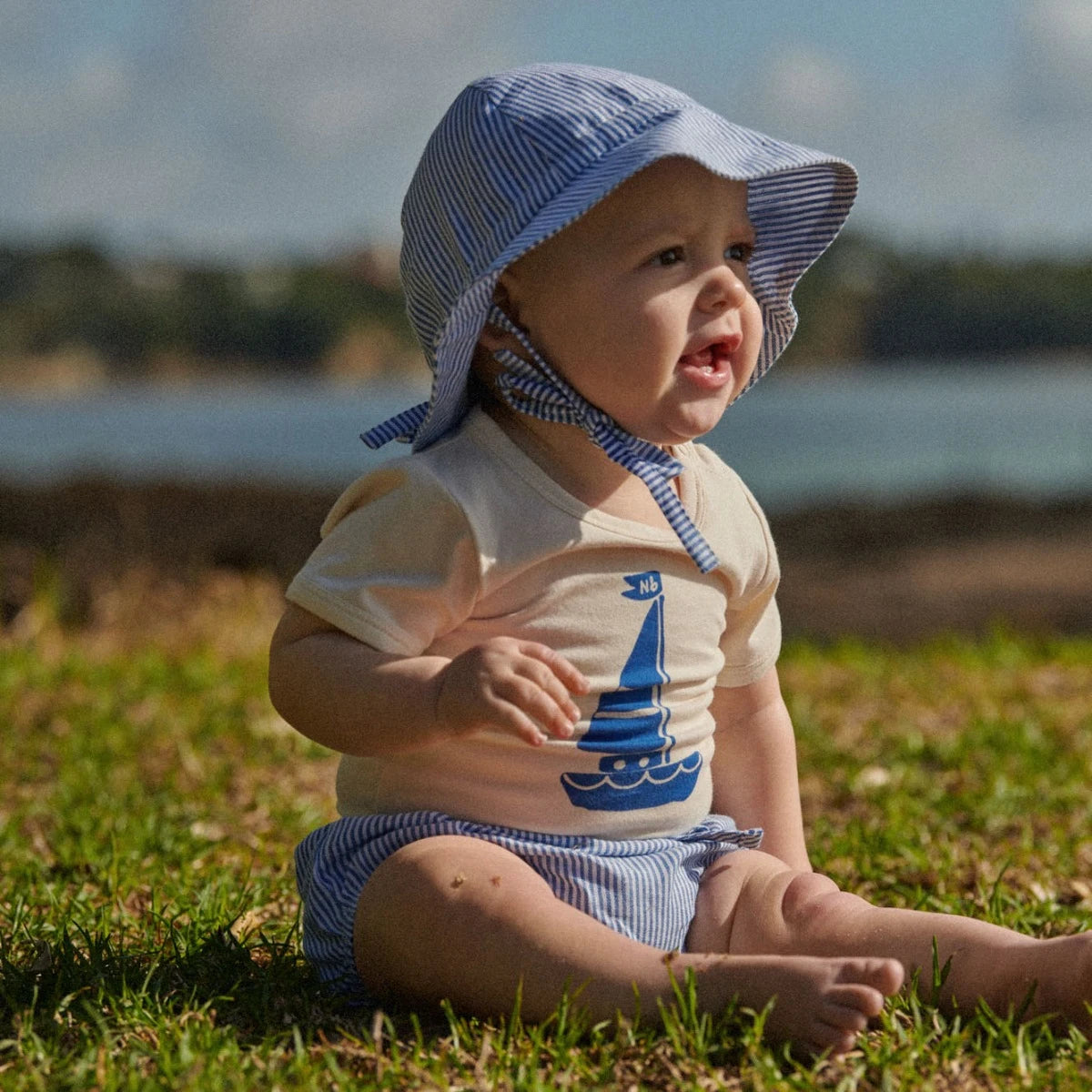 organic cotton baby onesie with blue sailboat print on the front