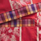 Flat lay detail of cotton fabric showing palm leaf print and plaid trim construction