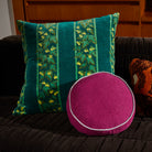 Agata Velvet Cushion styled on dark charcoal sofa with magenta round cushion in modern living room