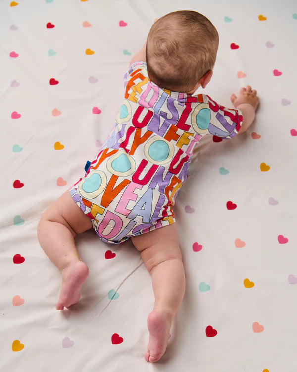 baby crawling wearing the Kip & Co x The Beatles All You Need Is Love Organic Short Sleeve Romper
