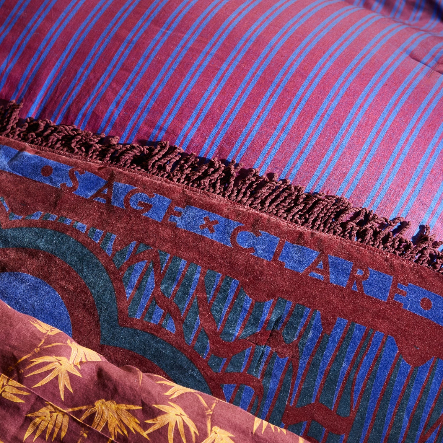 Detail view of red spotted snake pattern on blue velvet Andrea Bedcover with decorative fringe trim