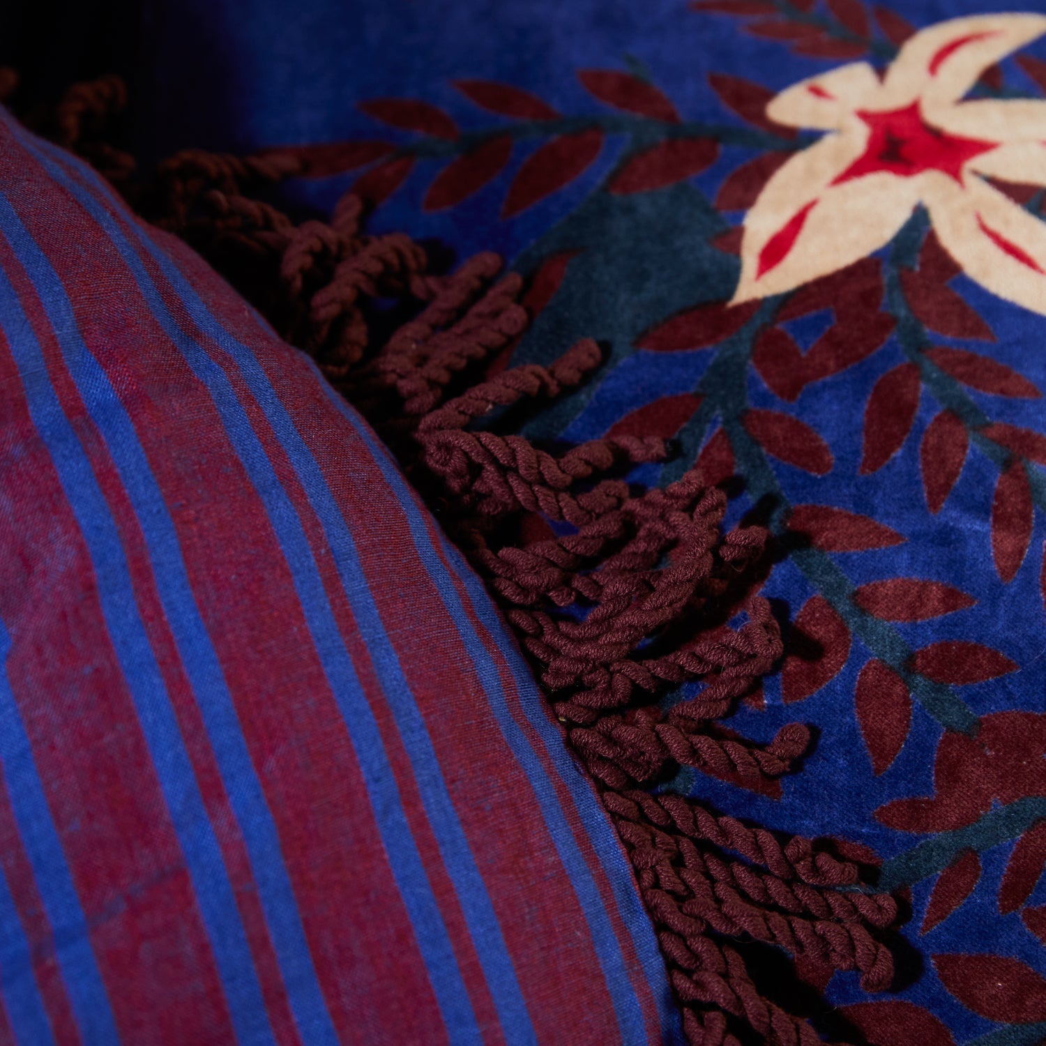 Close-up of striped reverse side fabric showing blue and burgundy pattern with rope fringe border