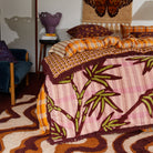 Close-up detail of Aneta Tufted Blanket showing geometric pattern border and burgundy tufted fringe trim