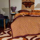 Side angle view of Aneta Tufted Blanket on bed showing pink palm motifs and layered textile styling