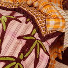 Close-up of chartreuse and burgundy tufted palm leaf details on pink striped Aneta blanket fabric