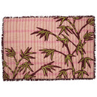 Detail view of burgundy tufted fringe edge and palm leaf embroidery on Aneta blanket corner