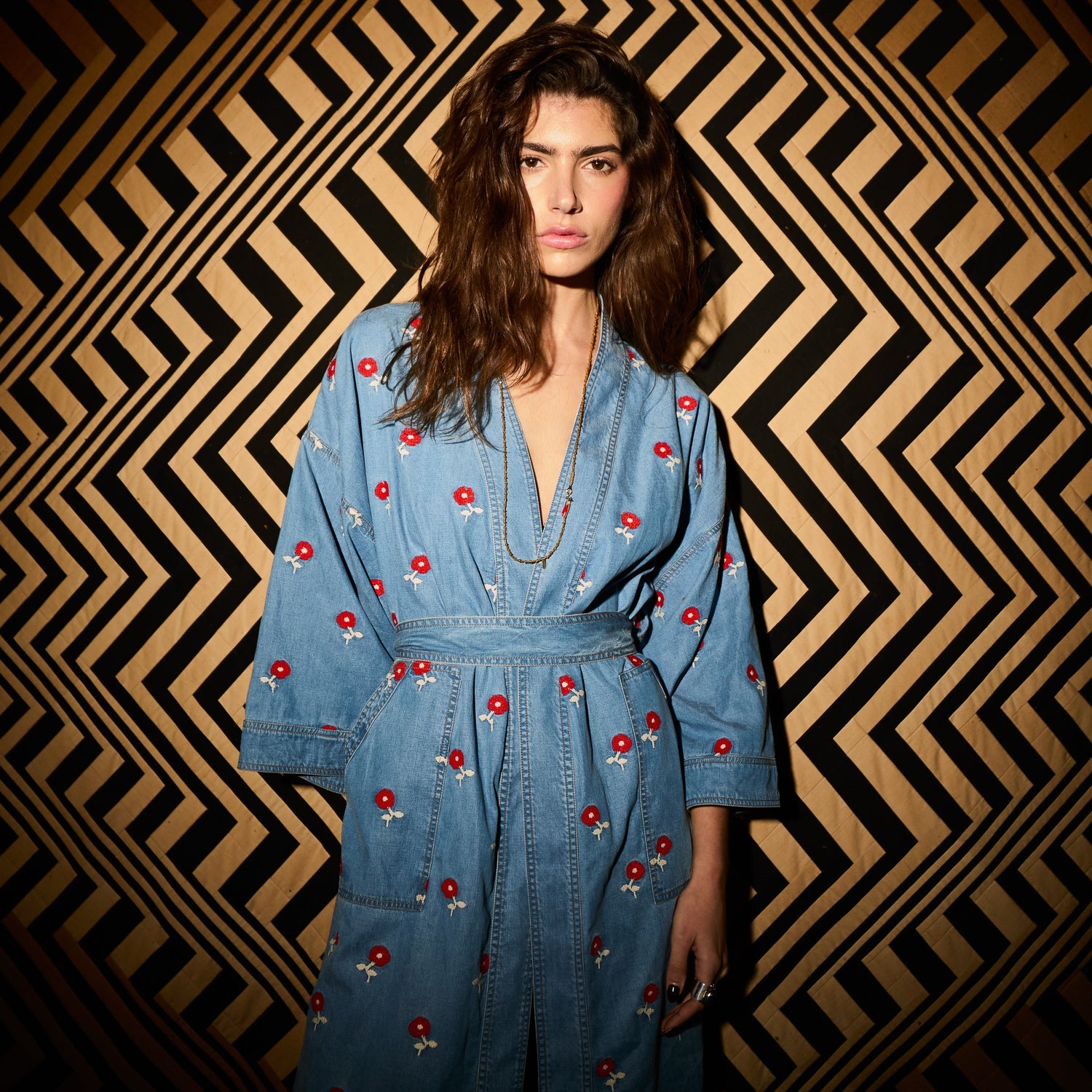 Front-on portrait view of light blue denim robe with all-over red embroidered flowers and wide kimono-style sleeves